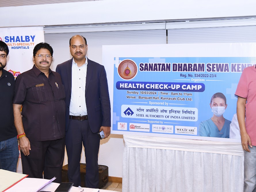 Organisers standing beside the Sanatan Dharam Sewa Kendra health camp banner